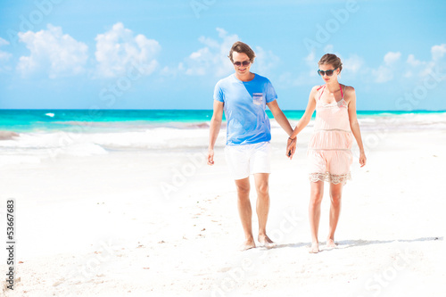 Young happy couple walking on beach smiling. Tulum, Mexico