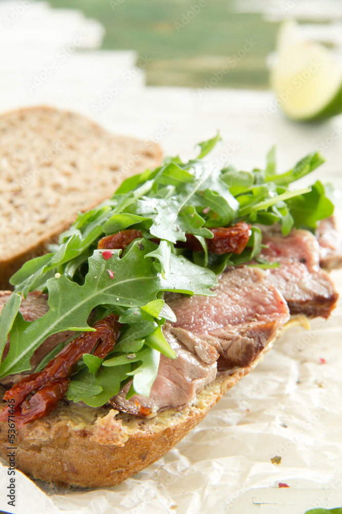 Bun with grilled roast beef and arugula. Bun with grilled roast beef and arugula.