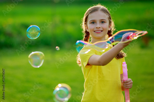Summer joy, young girl playing with soap bubbles