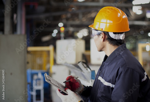 Factory worker writing on clipboard