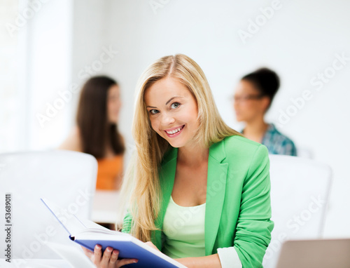 smiling student girl reading book at school