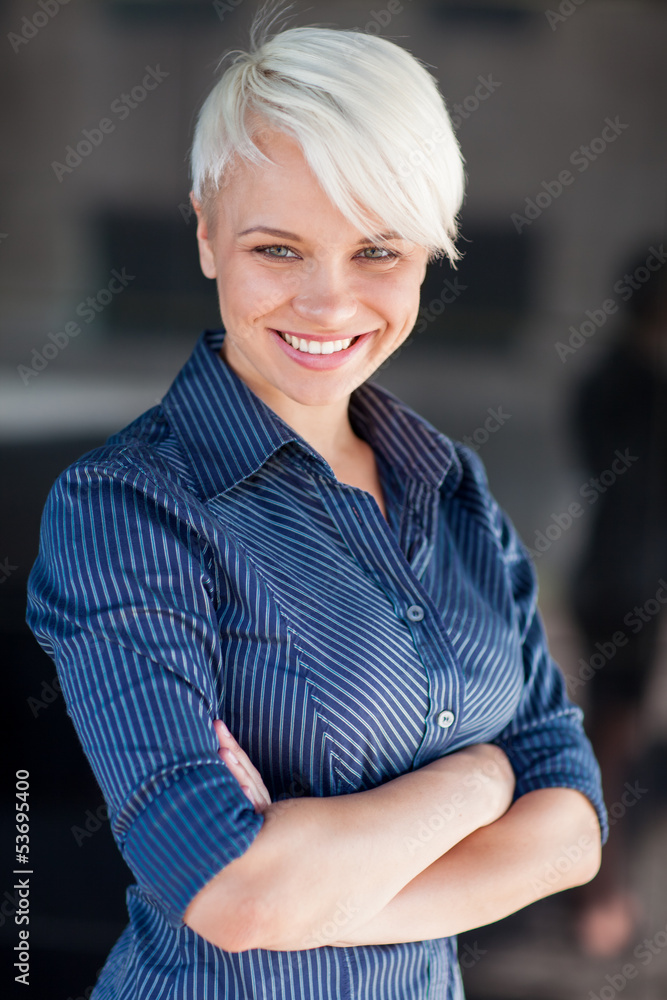 Businesswoman wearing shirt and smiling in front of a dark backg Businesswoman wearing shirt and smiling in front of a dark backg