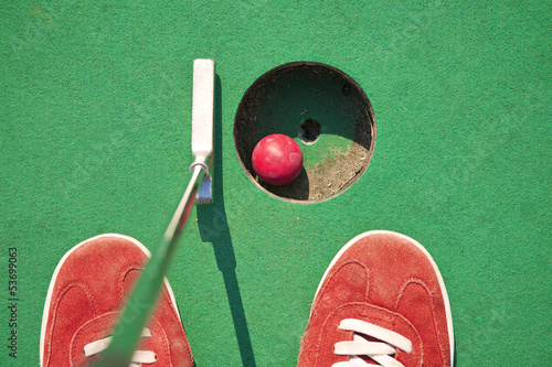 Close-up of miniature golf hole with bat and ball