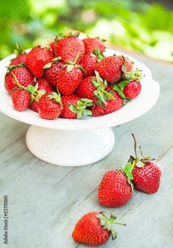 plate with red strawberries on a wooden textured table top