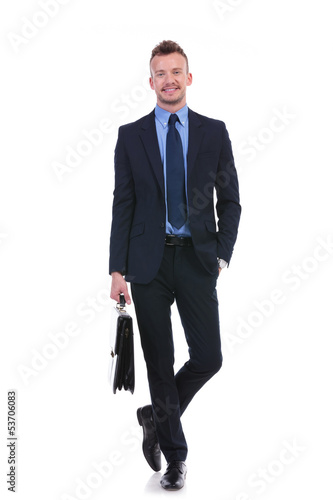 business man stands with suitcase and hand in pocket
