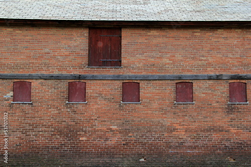 Old weathered red brick wall with boarded up windows
