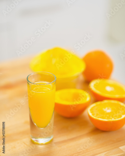 Closeup on glass of orange juice and oranges on cutting board