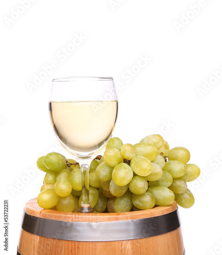 Ripe grapes and wine glass on a wooden barrel