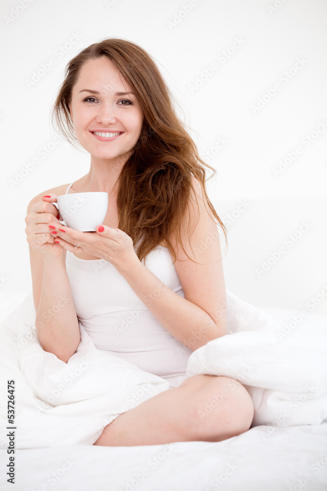 woman sitting on bed with cup