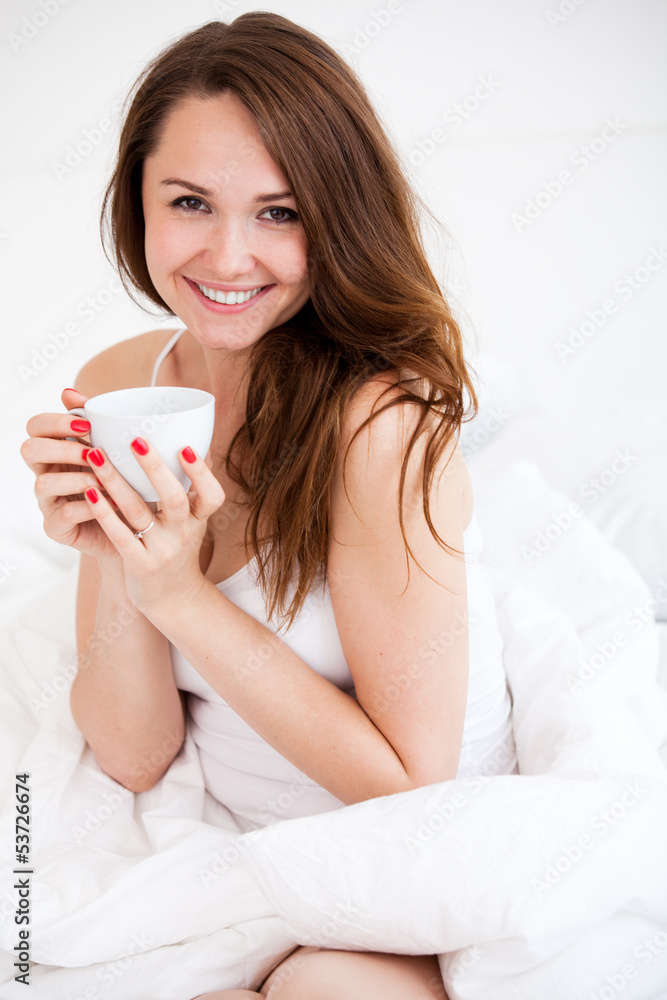 portrait of  woman in bed holding a cup