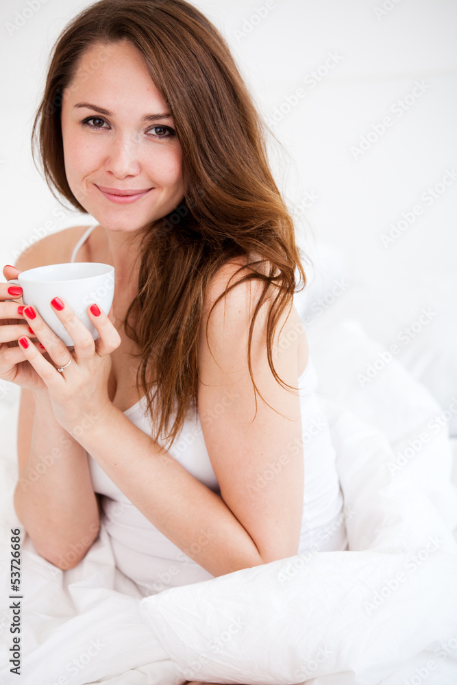 portrait of  woman in bed holding a cup
