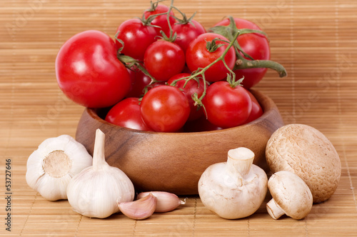 Fresh Tomatoes with champignon and garlic in wooden bowl