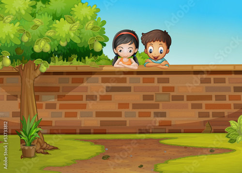 A girl and a boy leaning over the concrete fence