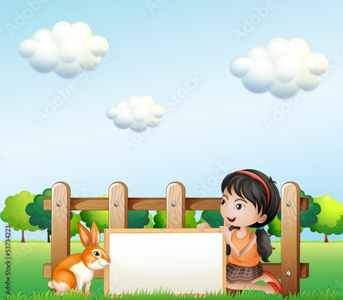 A girl holding a framed banner near the fence