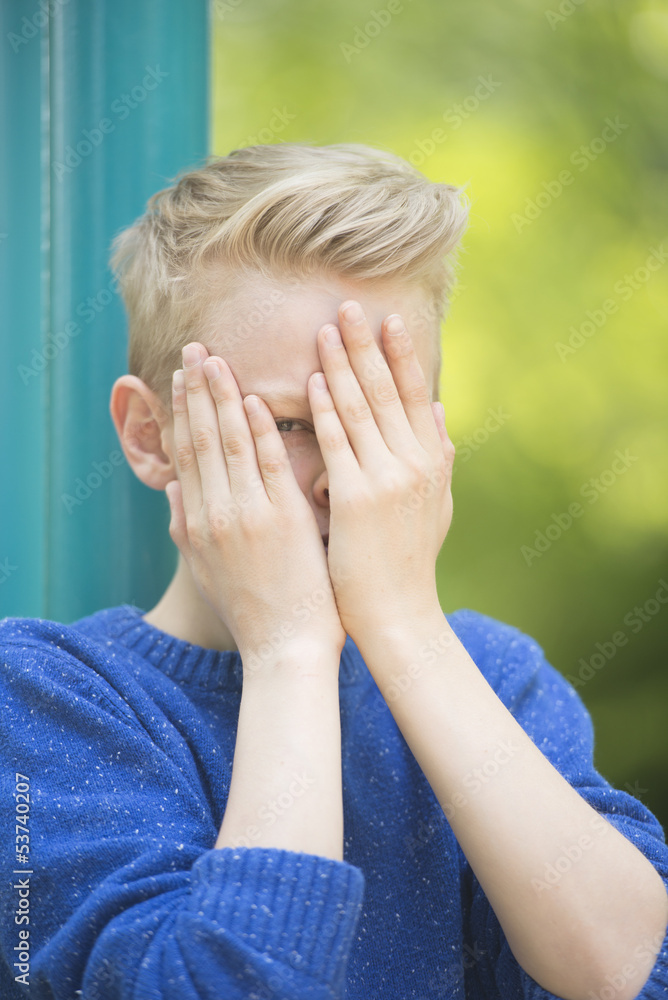 Young teenage boy gazing through fingers