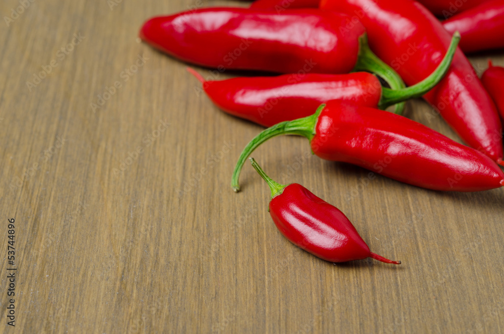 red hot chili peppers on wooden background with space for text