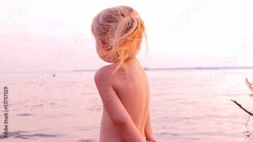 маленькая девочка играет, смотрит  вдаль на воду