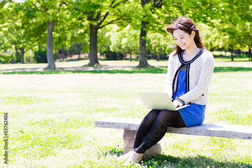 young asian woman using laptop in the park