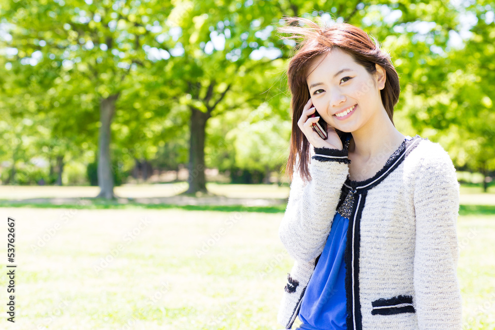 young asian woman using cellphone in the park young asian woman using cellphone in the park