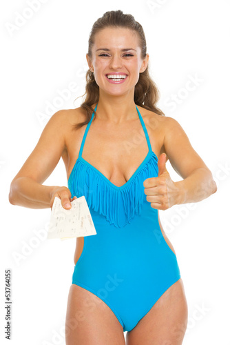 Happy young woman in swimsuit showing air tickets and thumbs up © Alliance