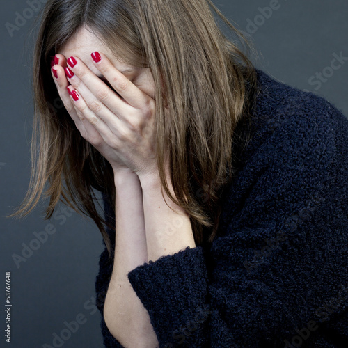 Frau versteckt ihr Gesicht in Händen photo