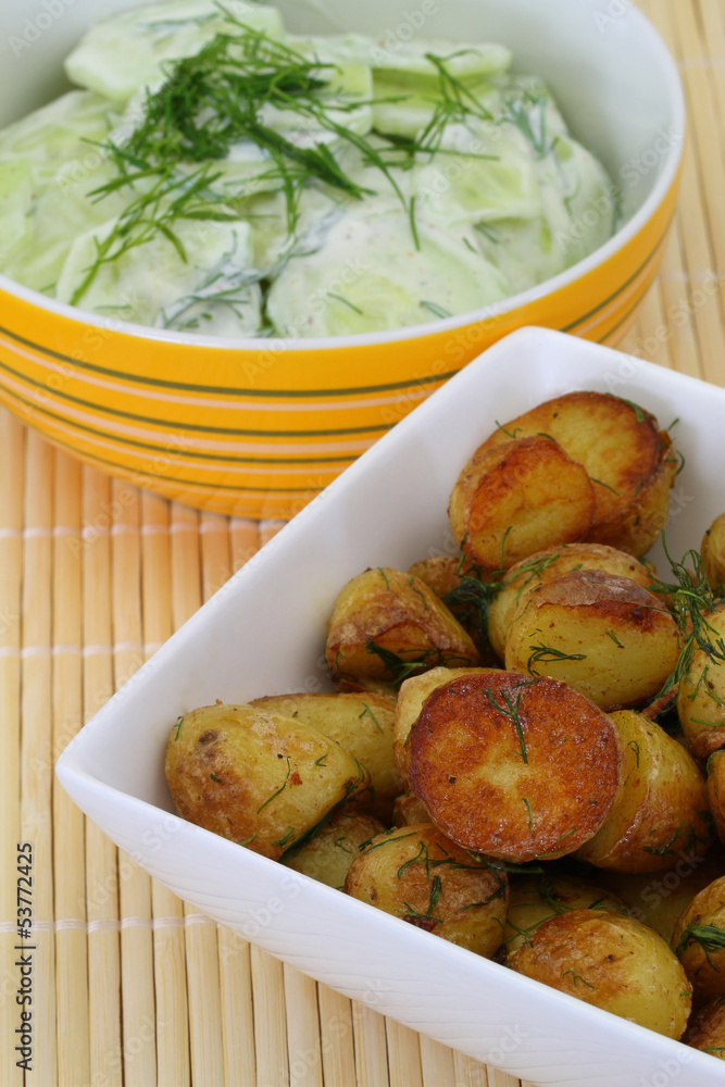 Side dishes of roasted potatoes and cucumber salad