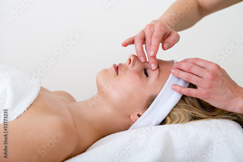 Masseuse massaging a woman eyebrow area.
