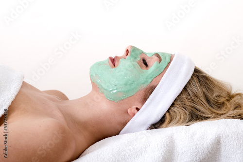 Blond woman enjoys facial beauty treatment.