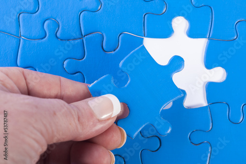 Obraz na plátne Woman's hand placing missing piece in Jigsaw puzzle  signifying