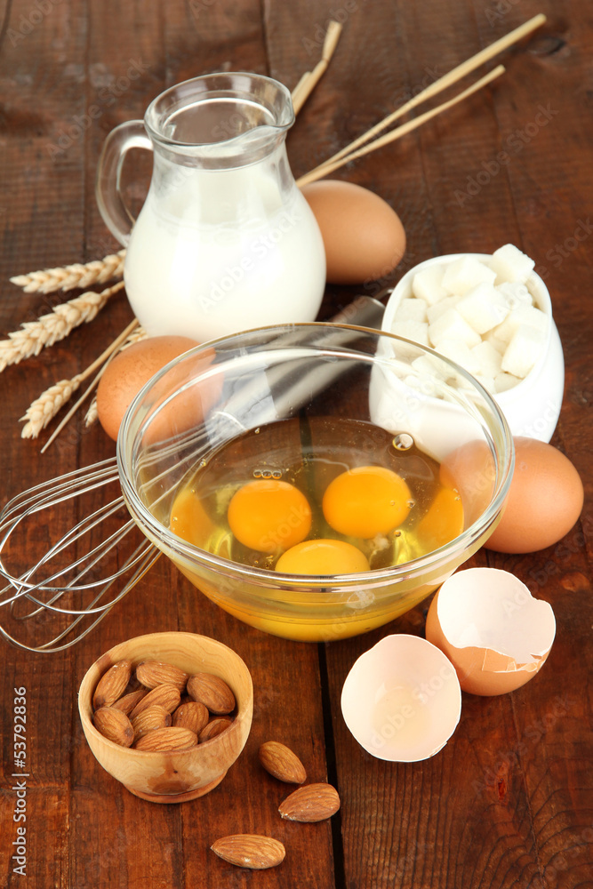 Broken egg in bowl and various ingredients next to them Broken egg in bowl and various ingredients next to them