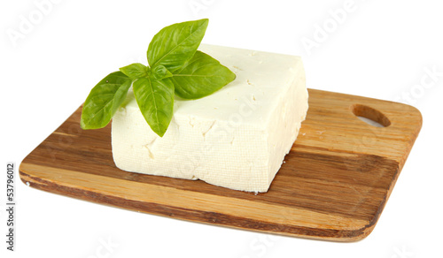 Sheep milk cheese with basil on cutting board, isolated on