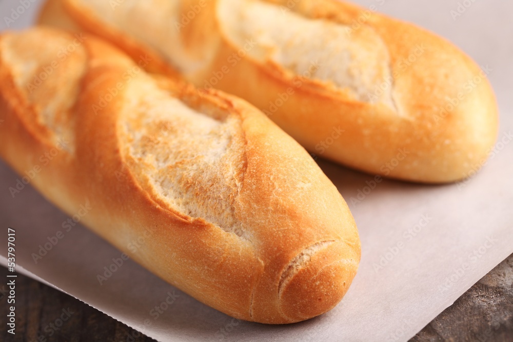 Two fresh baguettes on baking paper. Selective focus.