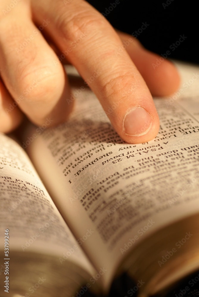 Fototapeta premium Close-up of Bible opened on Psalm 23 and pointing finger