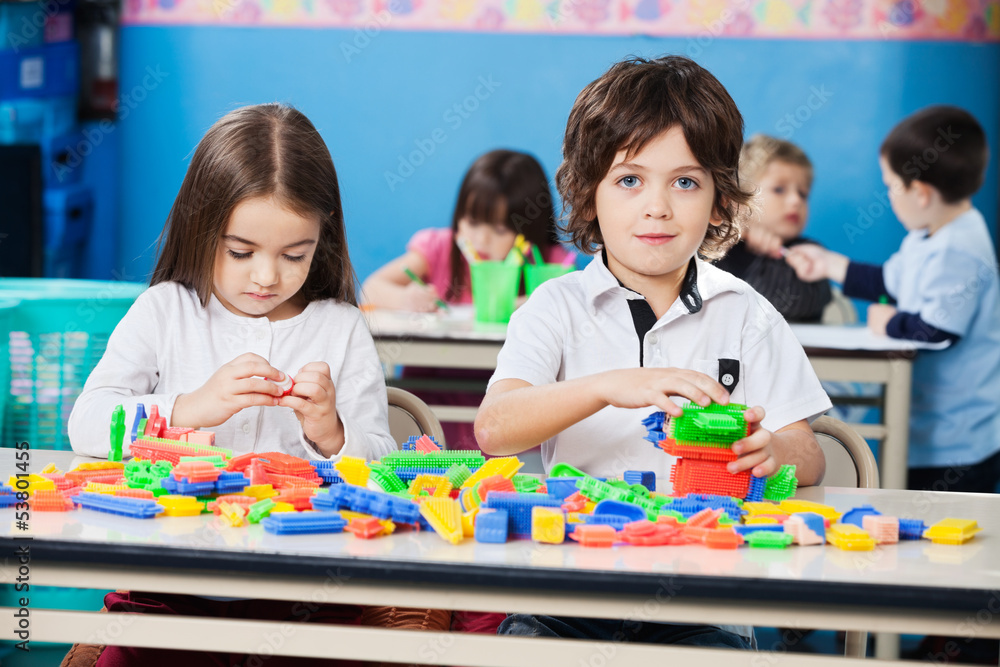 Fototapeta premium Boy With Female Friend Playing Blocks In Kindergarten
