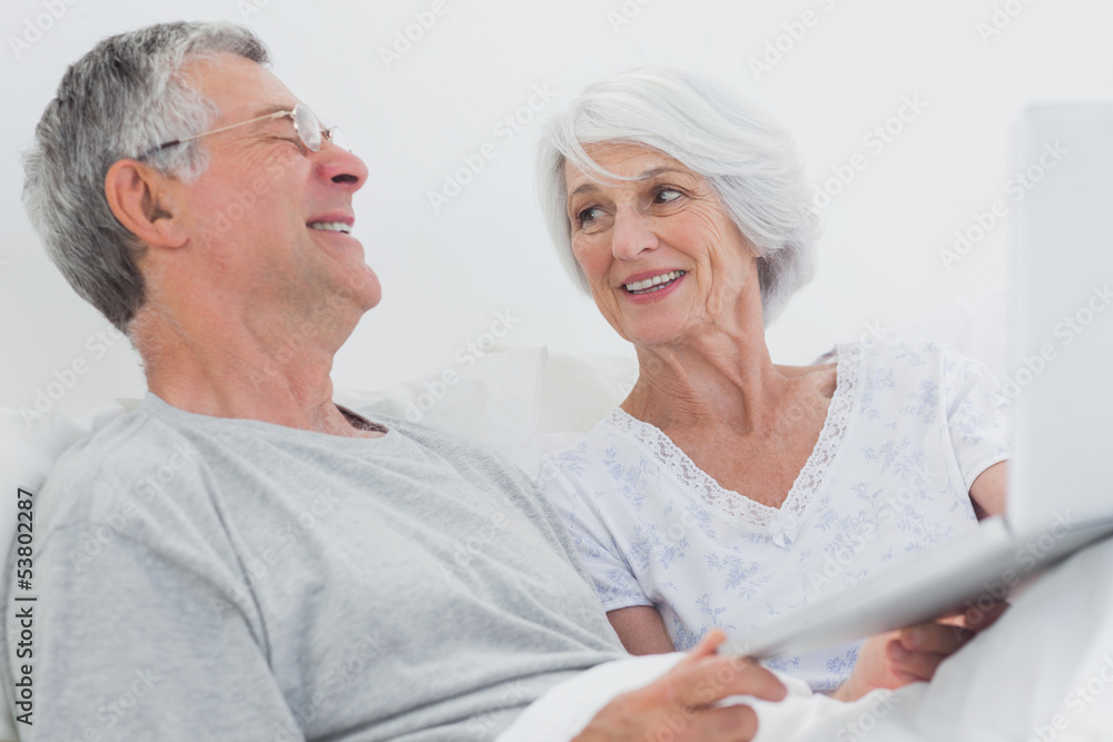 Cheerful mature couple using a laptop together Cheerful mature couple using a laptop together