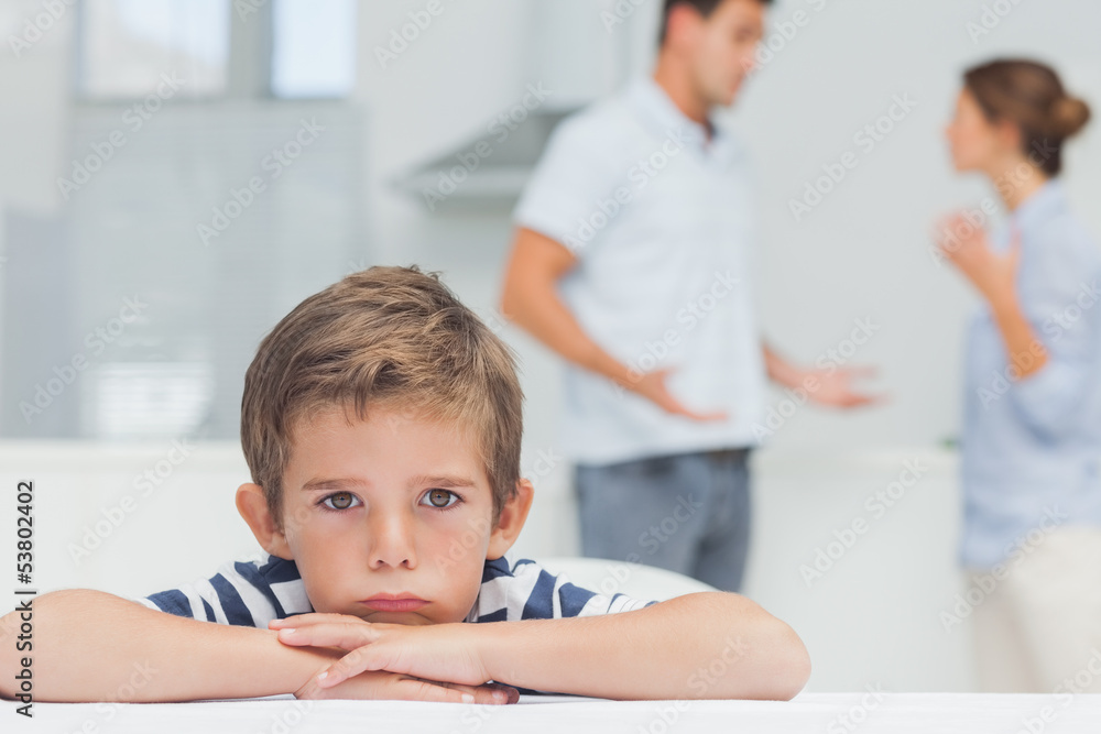 Sad boy with arms folded while parents quarreling Sad boy with arms folded while parents quarreling