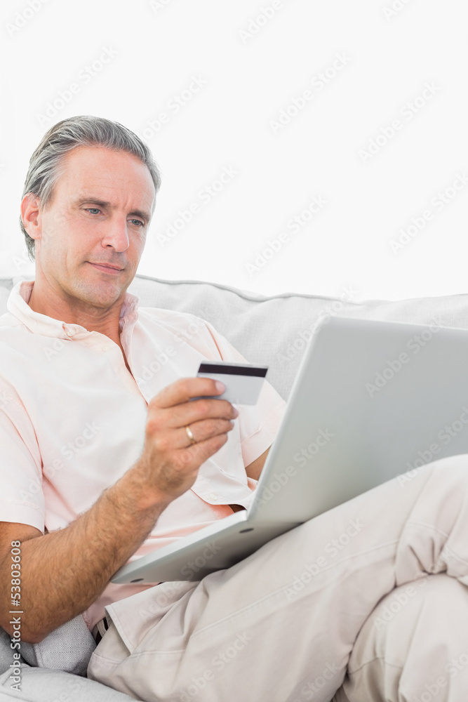 Man on his couch using laptop for shopping online Man on his couch using laptop for shopping online