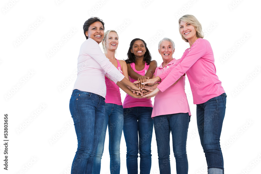 Obraz premium Cheerful women wearing breast cancer ribbons with hands together
