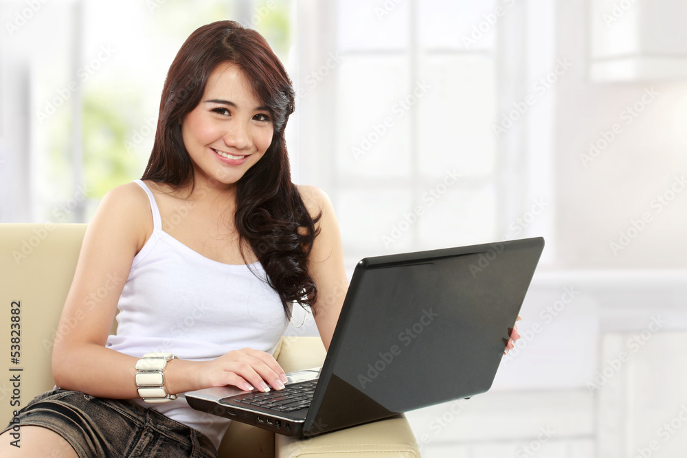 young asian woman sitting in sofa using a laptop young asian woman sitting in sofa using a laptop