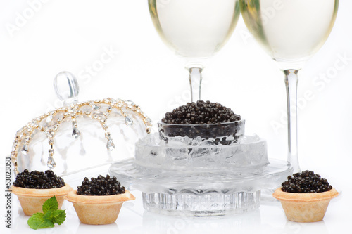 Black caviar and champagne in glass on a white photo