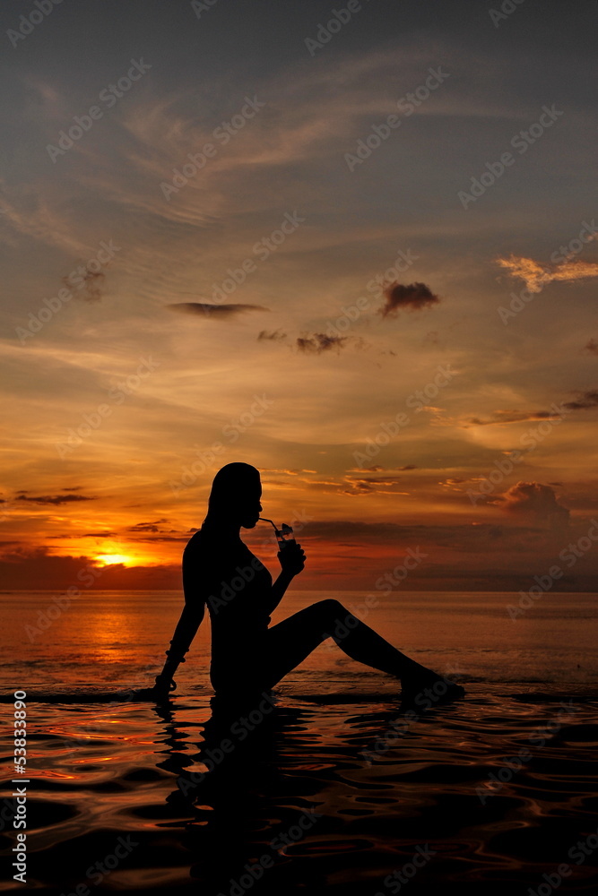 a beautiful young woman drinking cocktail on the beach