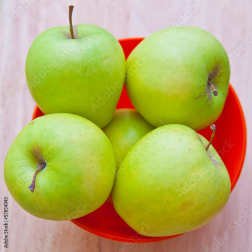 Green apples in a red bowl