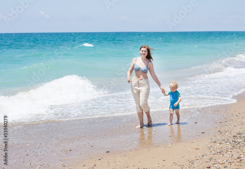 Happy mother and little baby son having fun at beach vacation