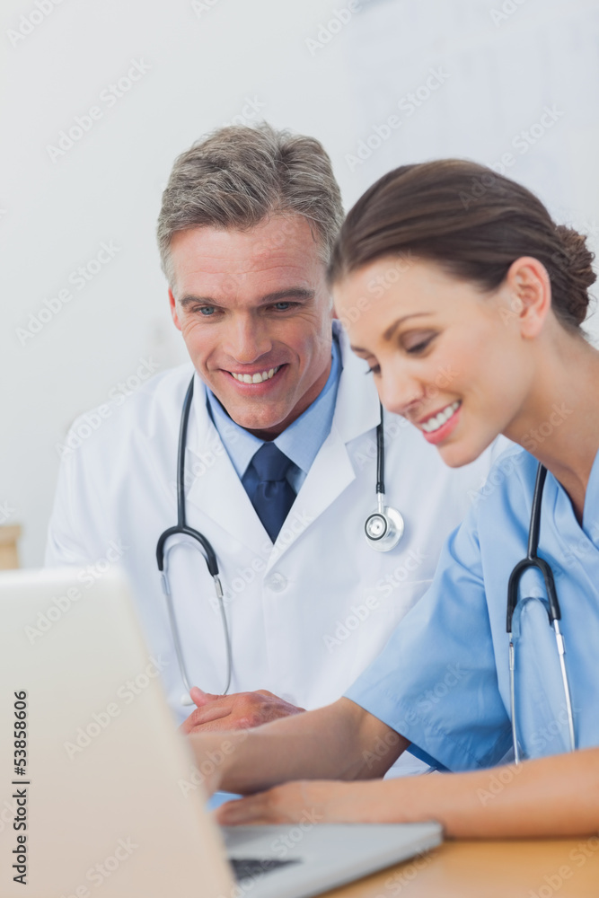 Fototapeta premium Two cheerful doctors working on a laptop