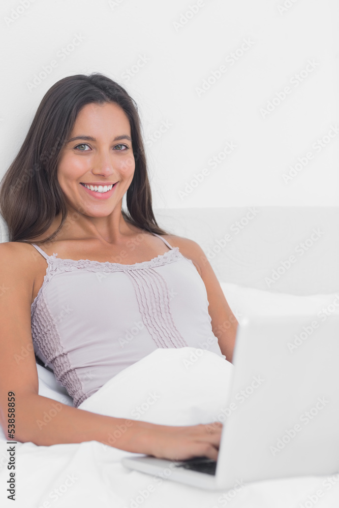 Portrait of a woman using her laptop in bed Portrait of a woman using her laptop in bed