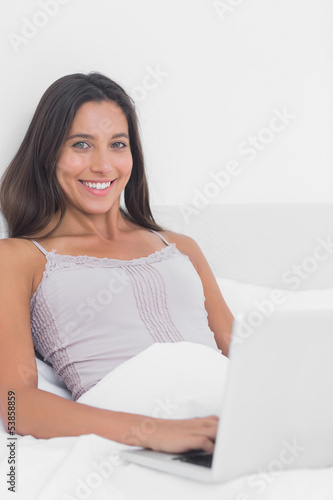 Portrait of a woman using her laptop in bed