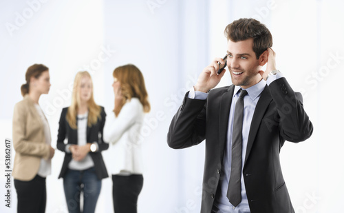 Businessman on phone with colleagues in the background