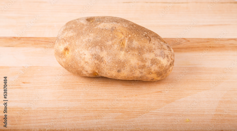 Whole Potato on Wood Cutting Board Whole Potato on Wood Cutting Board