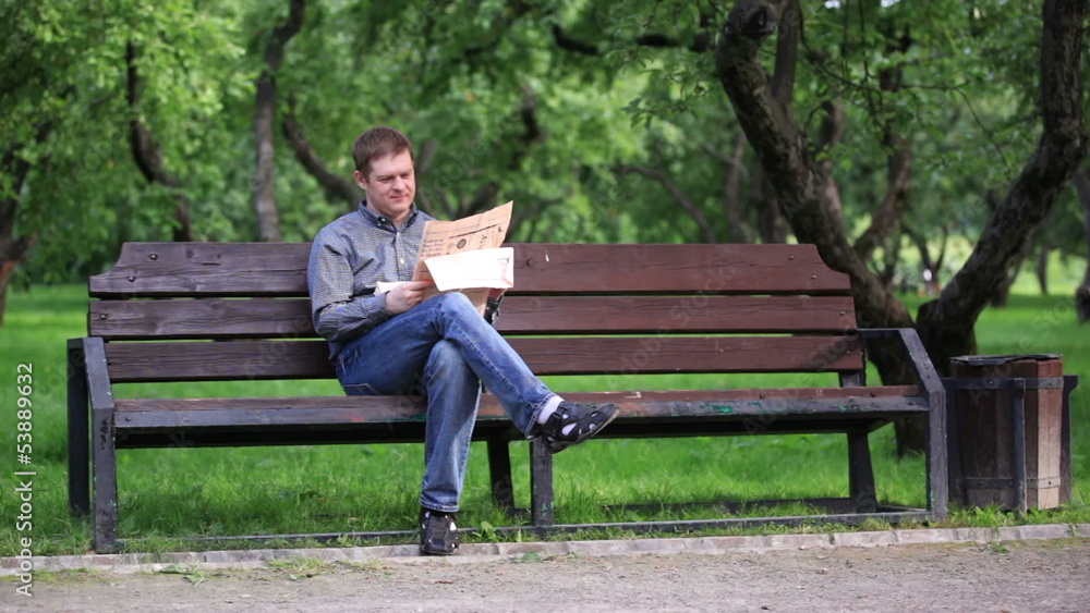 Man reads newspaper on bench in the park 1 Man reads newspaper on bench in the park 1