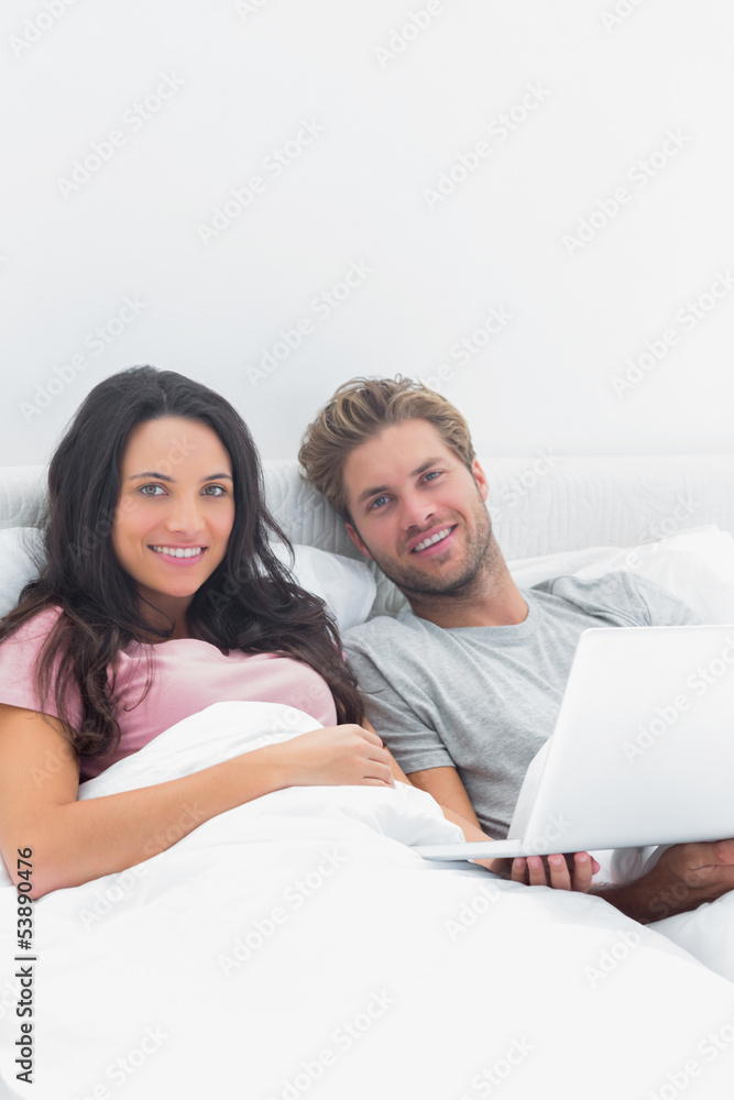 Couple using a laptop in bed Couple using a laptop in bed